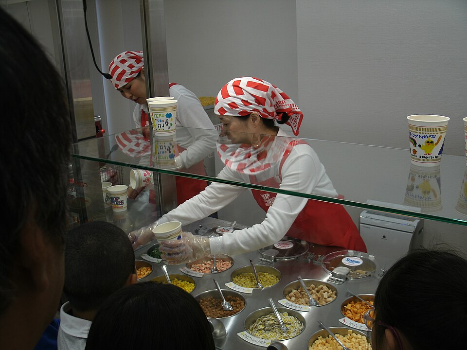 Staff adding selected toppings at My CUPNOODLES Factory in Ikeda