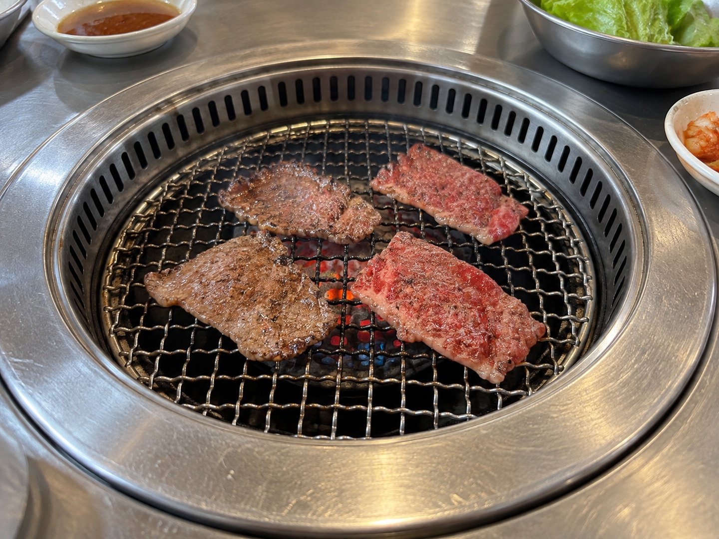 일반 식당 금속 테이블에 설치된 둥근 석쇠 위의 야키니쿠 그림