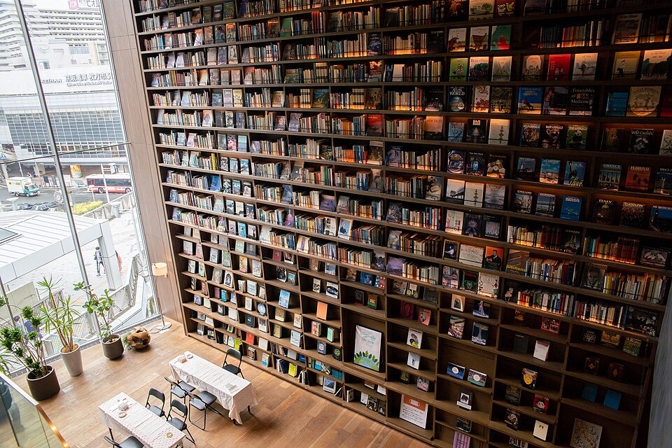 A bright reading space beside tall bookshelves at Hirakata Tsutaya Books