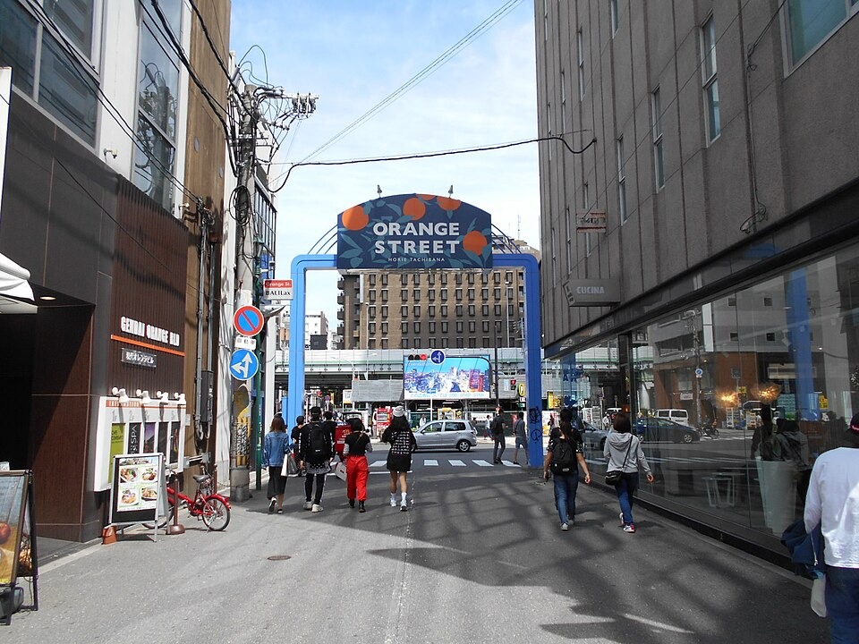 Shops and pedestrians by the Orange Street sign in Horie
