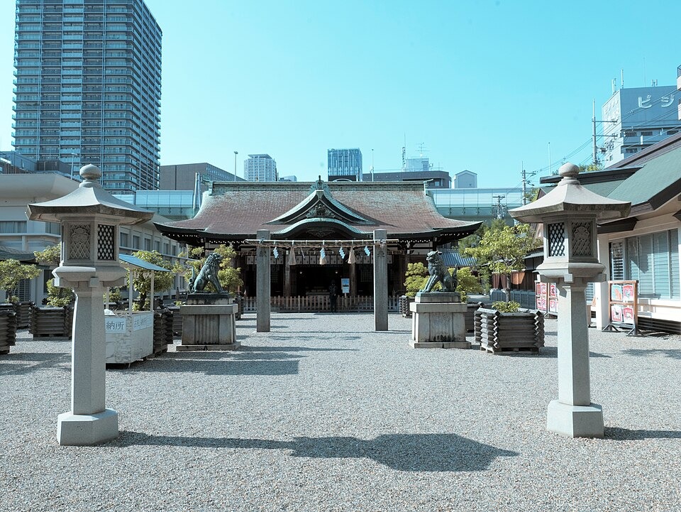 Stone lanterns and the shrine hall at Imamiya Ebisu Shrine in daylight