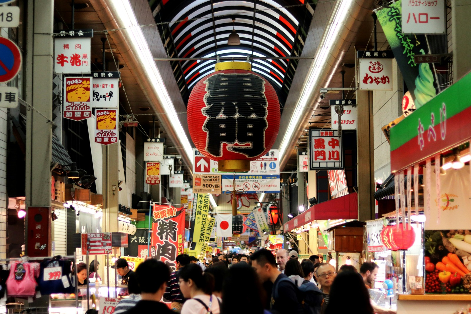Shoppers and food stalls beneath the large Kuromon Market lantern