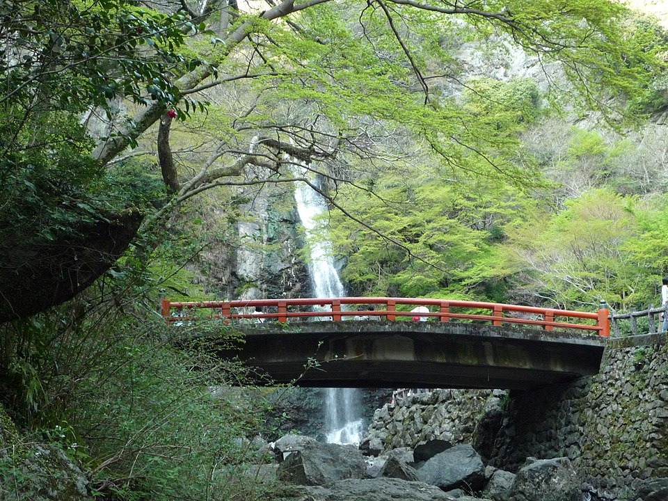 Minoh Falls beyond a red bridge and fresh green trees