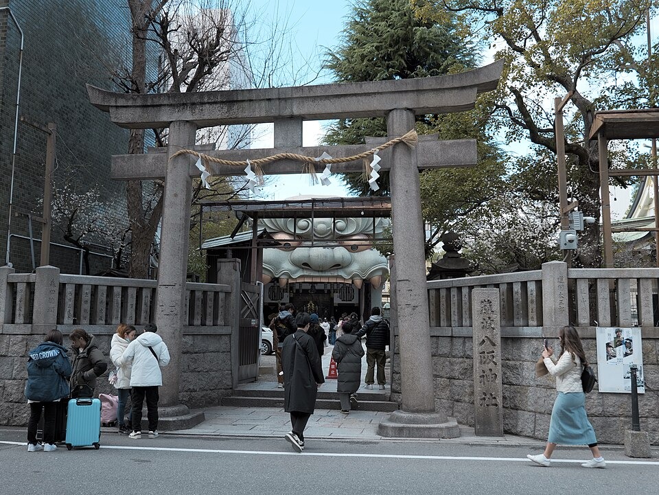 The stone torii and lion-shaped stage at Namba Yasaka Shrine with visitors approaching