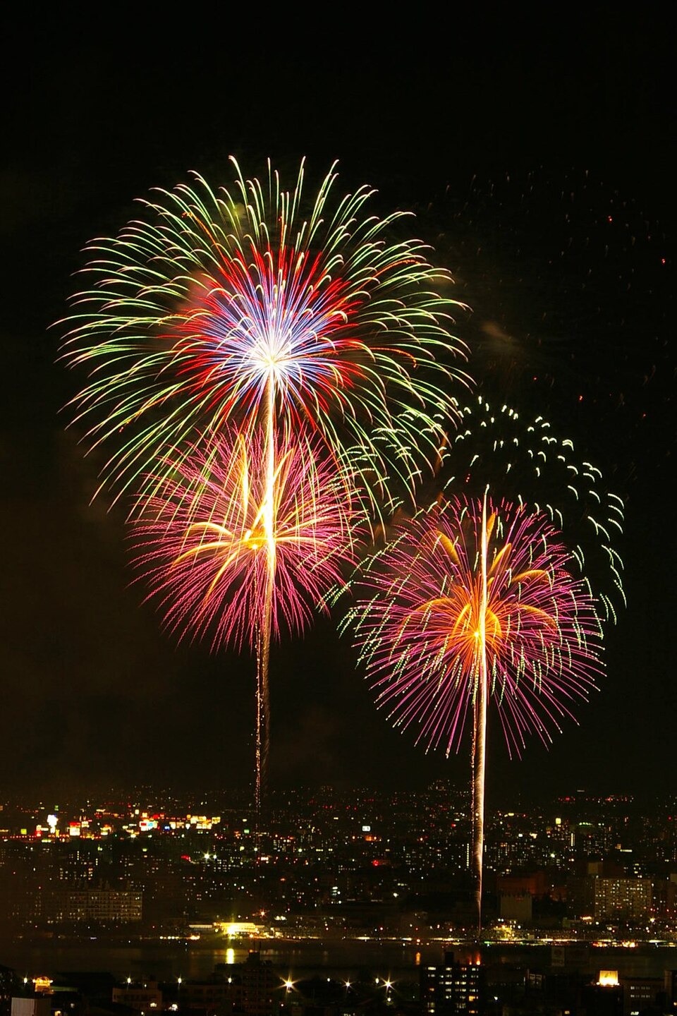 Colorful fireworks over the river and spectators at the Yodogawa fireworks event