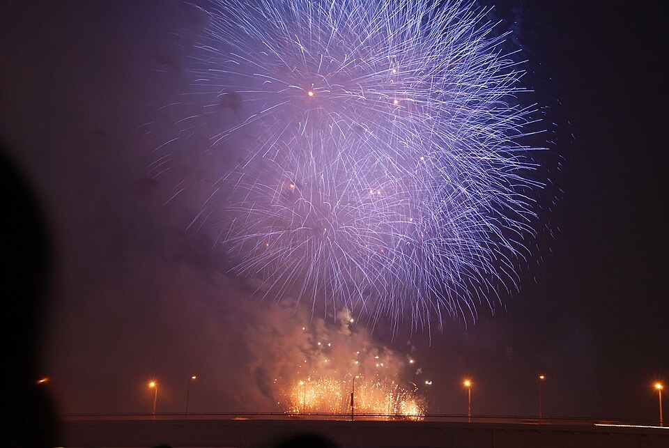 Large bursts of fireworks filling the sky above the Yodogawa River