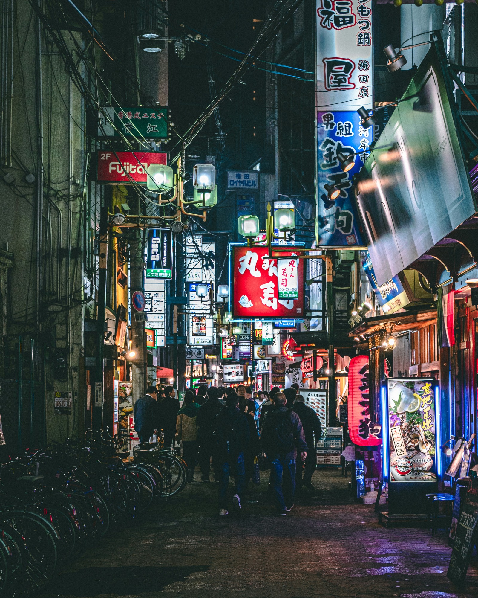 People walking among bright restaurant signs in a Umeda dining street at night