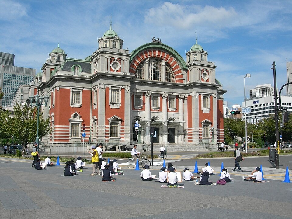 People sketching the red-brick Osaka City Central Public Hall on a sunny day