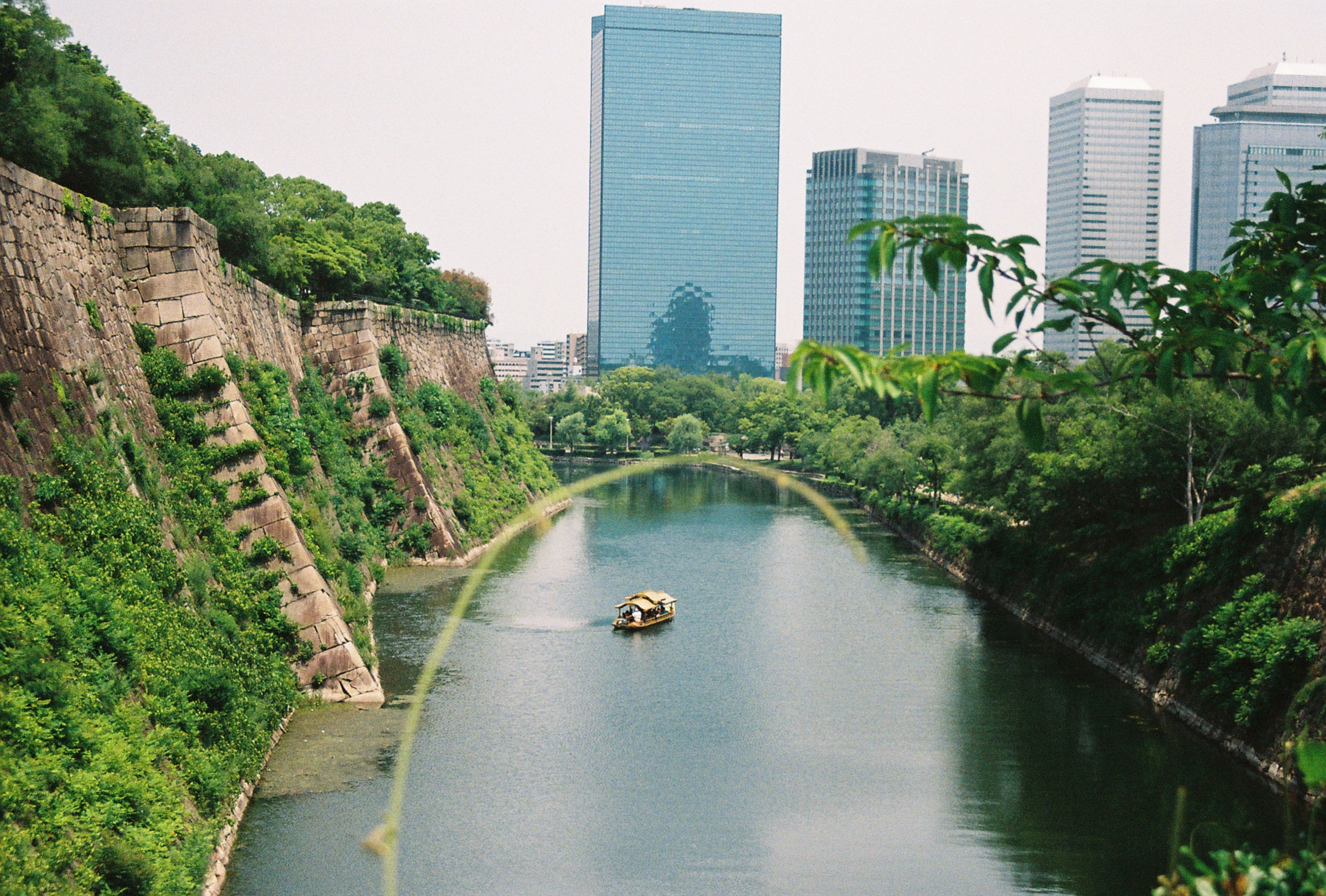 A sightseeing boat on the moat beside the stone walls of Osaka Castle