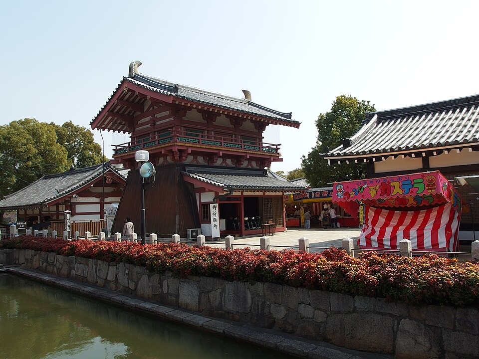 Visitors beside the traditional temple hall and tiled roofs at Shitennoji