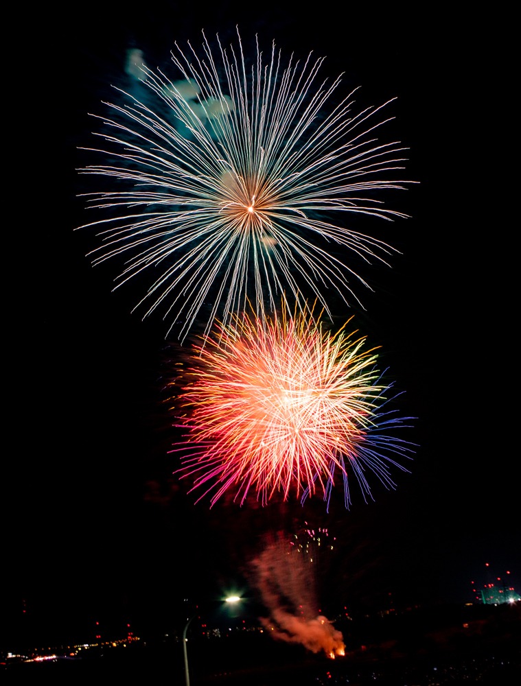 Red and green fireworks bursting above Hirakata at night