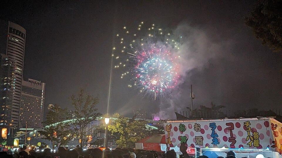 Fireworks above festival visitors and boats along the Okawa River during Tenjin Matsuri