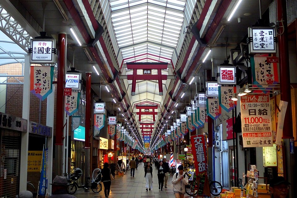 Shoppers walking beneath red torii decorations in Tenjinbashisuji Shopping Street