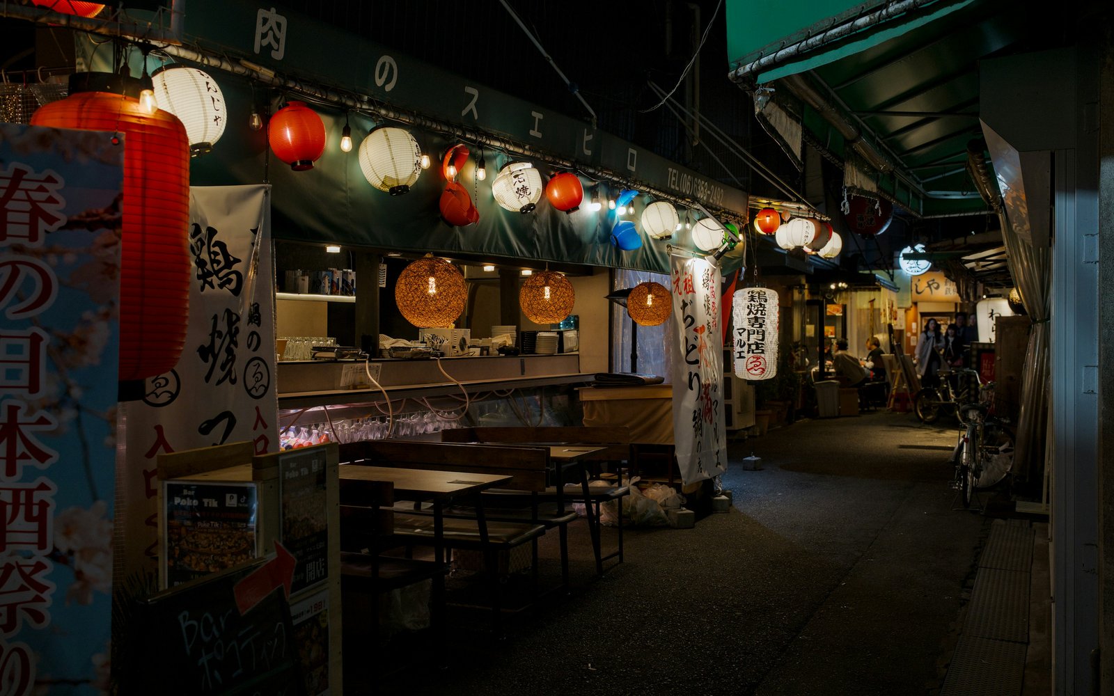 เคาน์เตอร์ร้านอาหารใต้แสงโคมไฟข้างตรอกอาหารแคบ